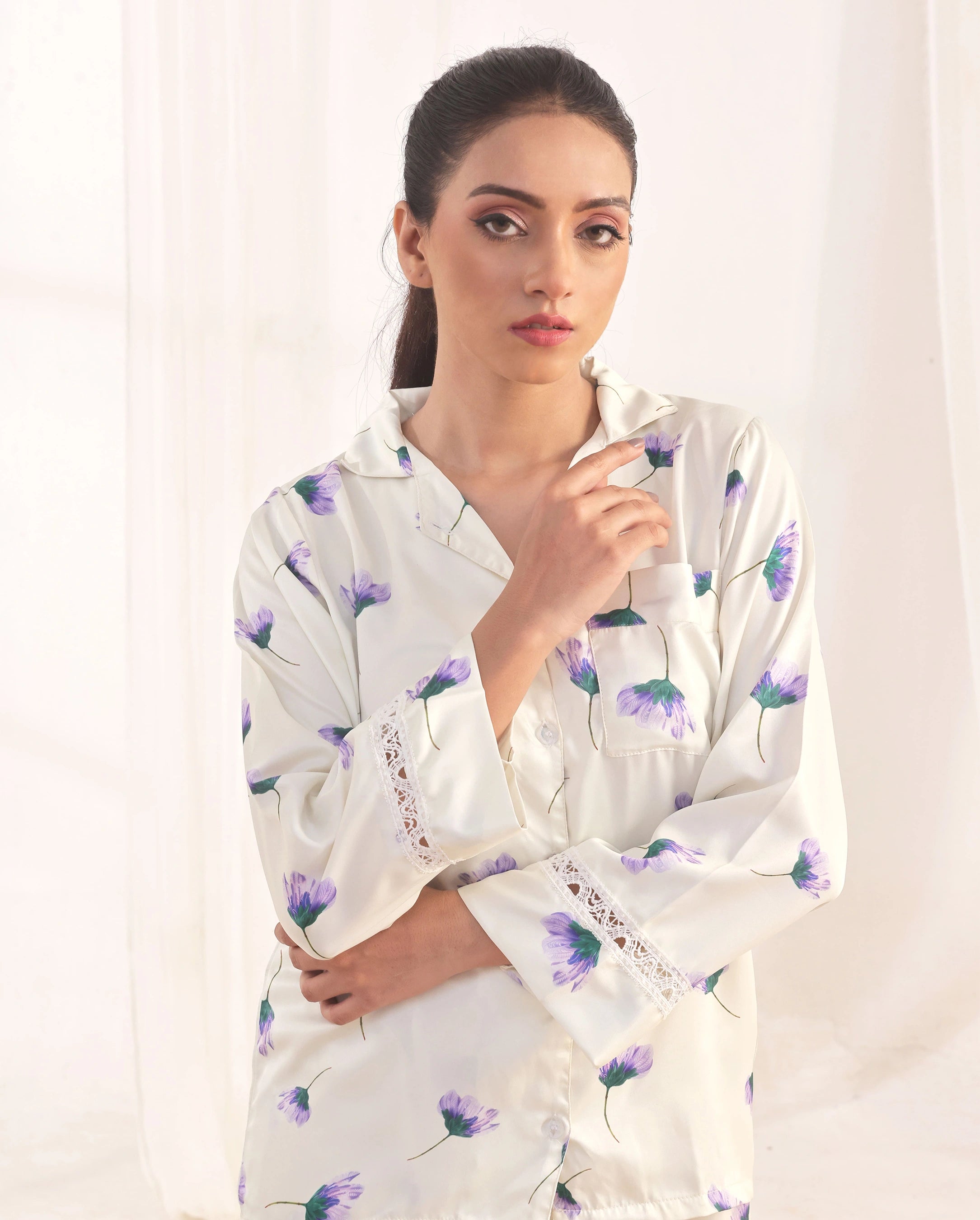 Woman wearing a white floral pajama set against a plain background