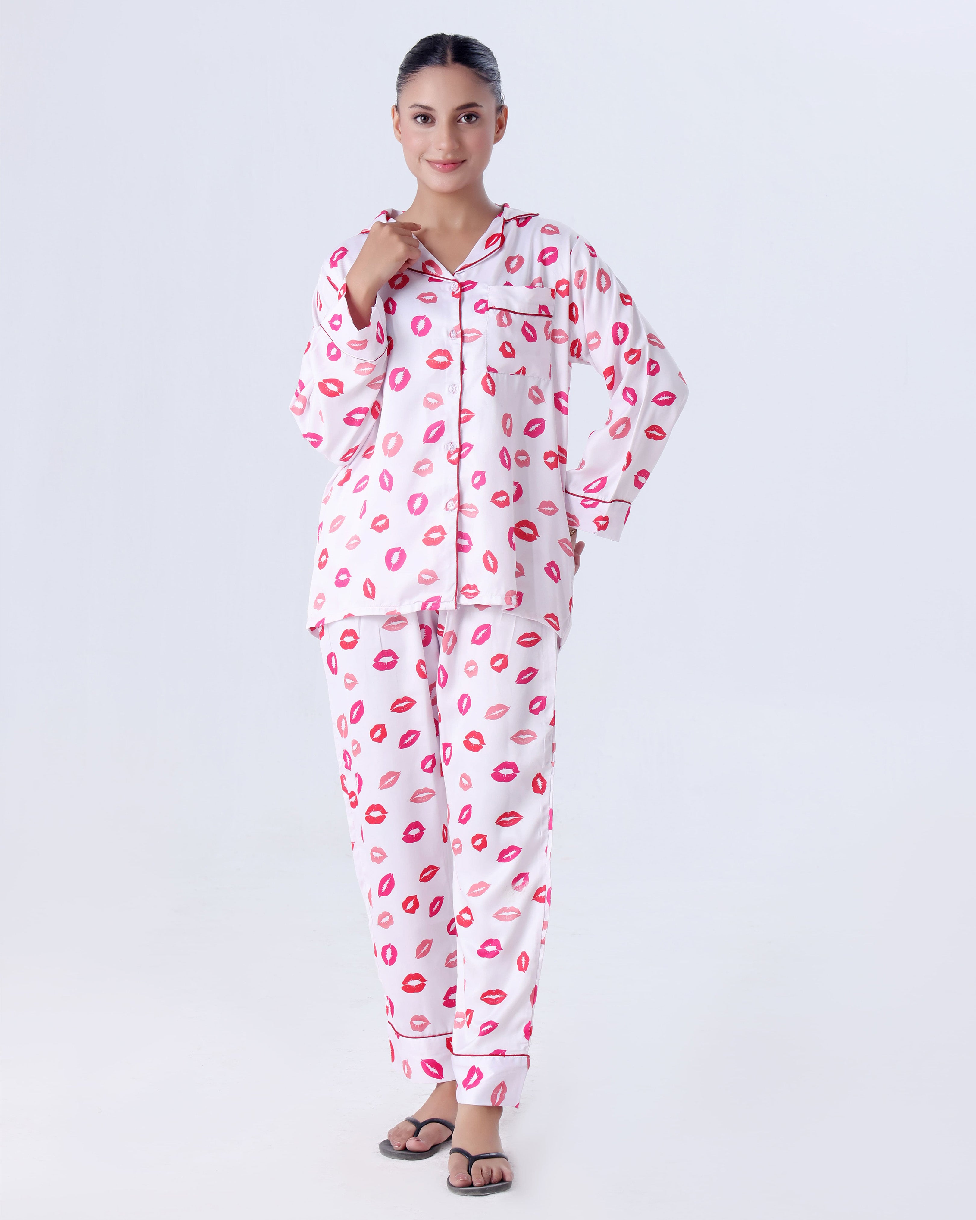 Woman wearing a pajama set with pink lip prints on a white background
