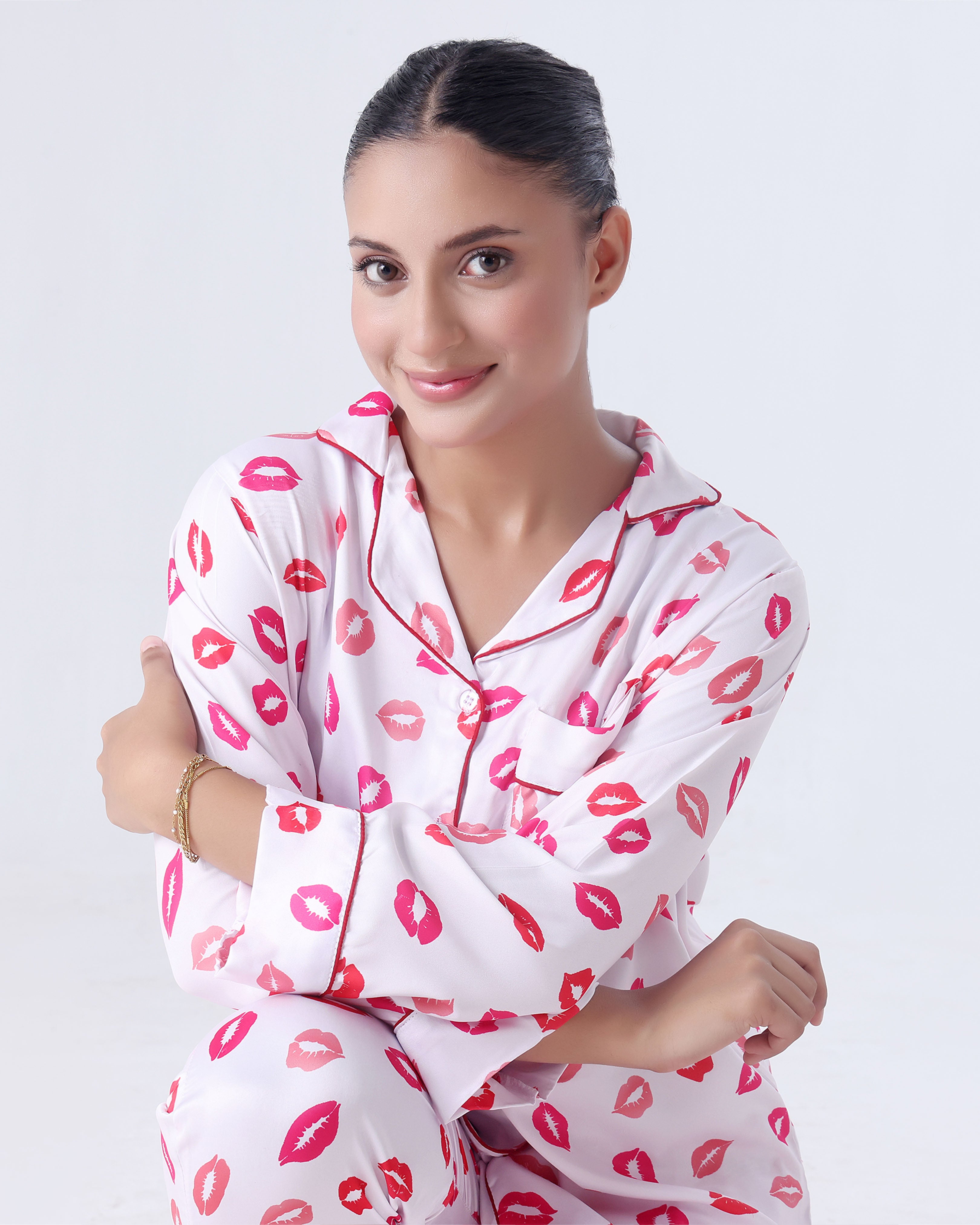 Woman wearing a white pajama set with pink lip prints on a light gray background