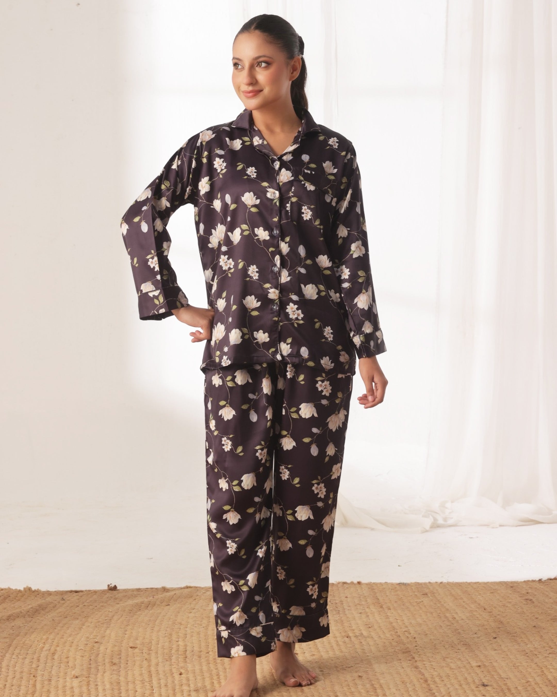 Woman wearing a floral pajama set against a white curtain background