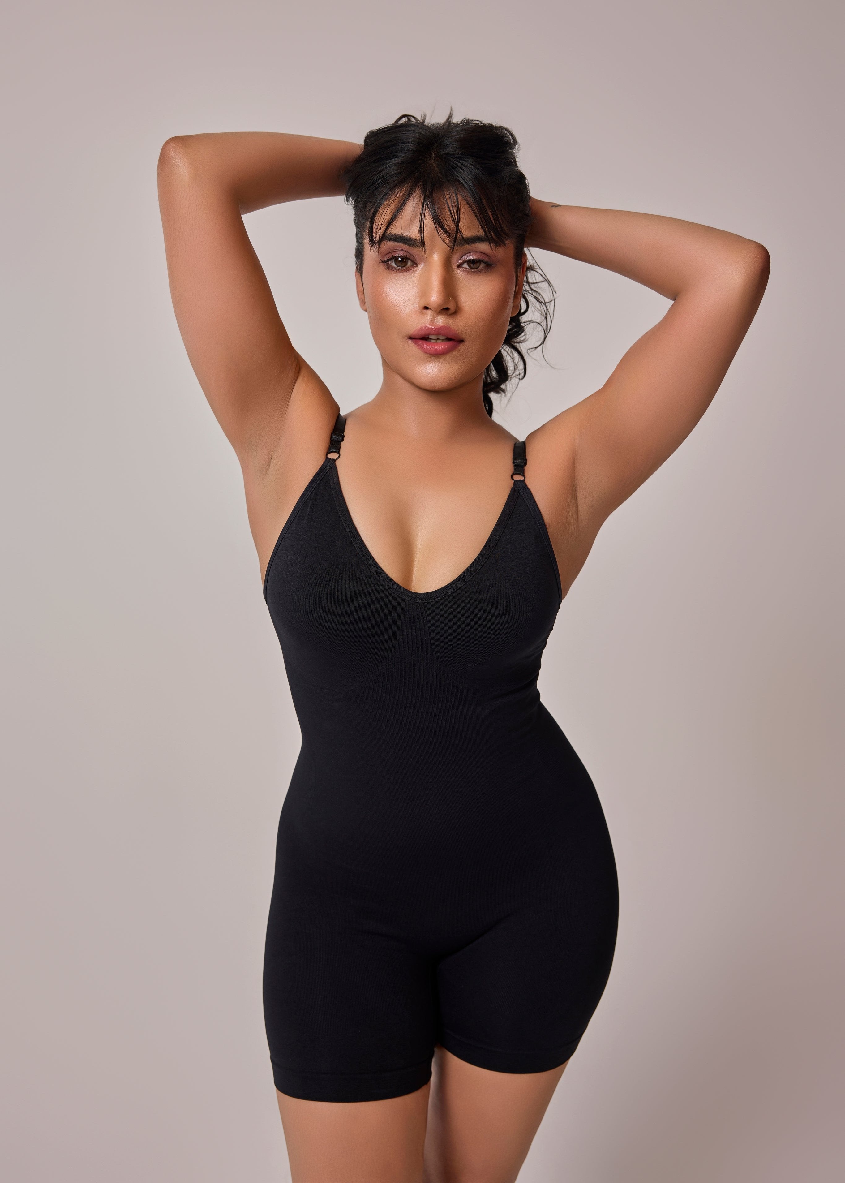 Woman wearing a black bodysuit against a plain background