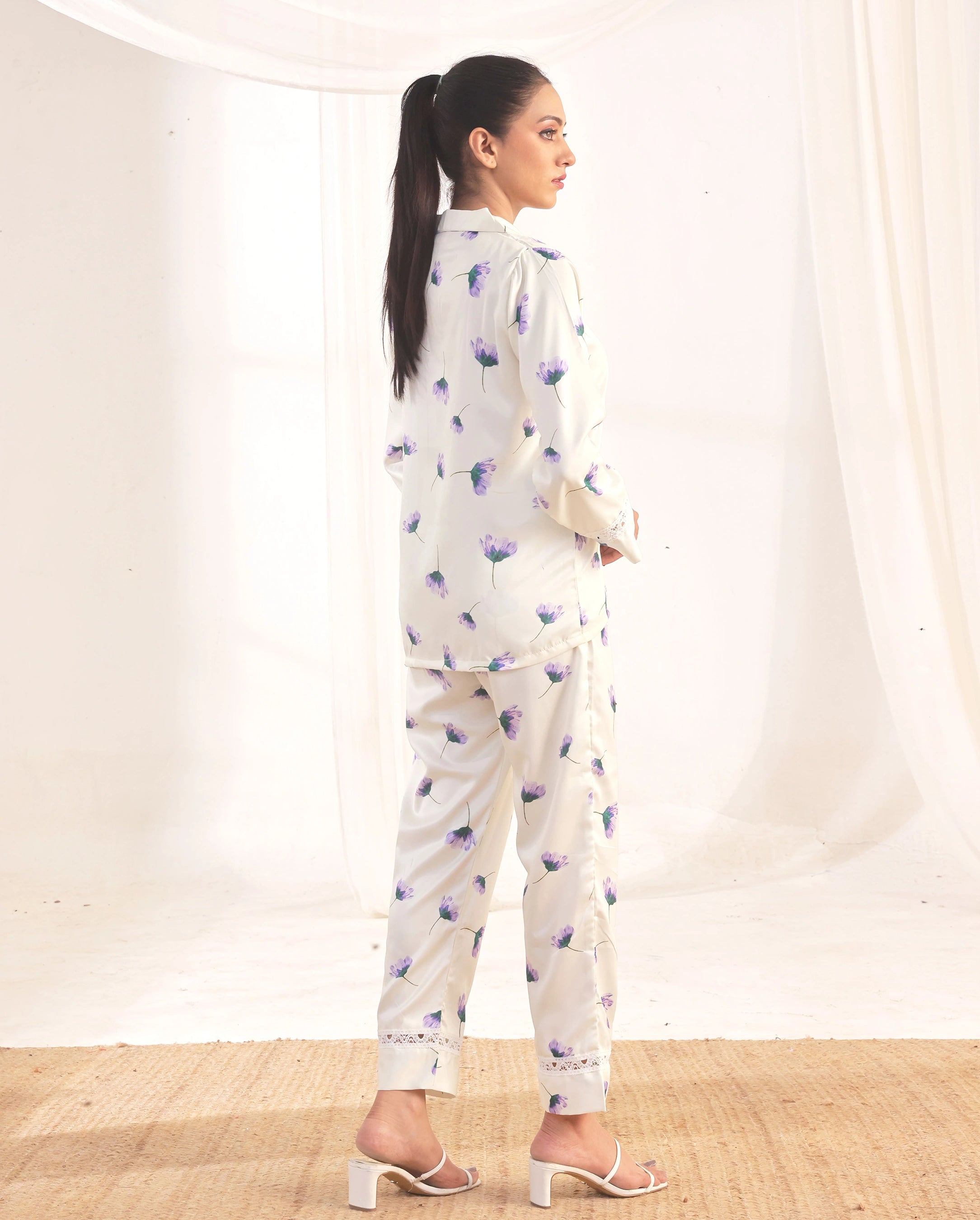 Woman wearing a white outfit with blue floral patterns against a plain background