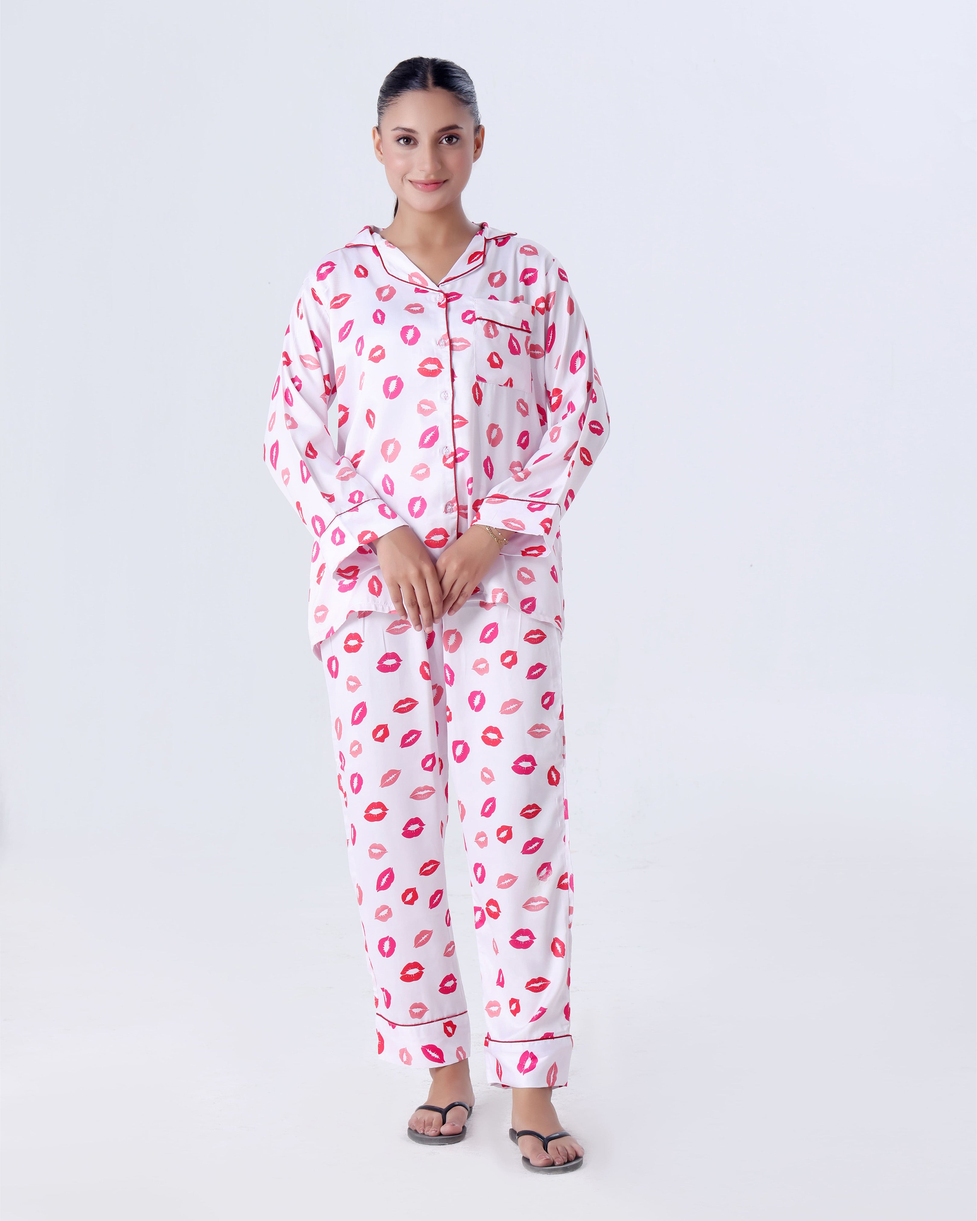 Person wearing a pink and red lip print pajama set on a white background