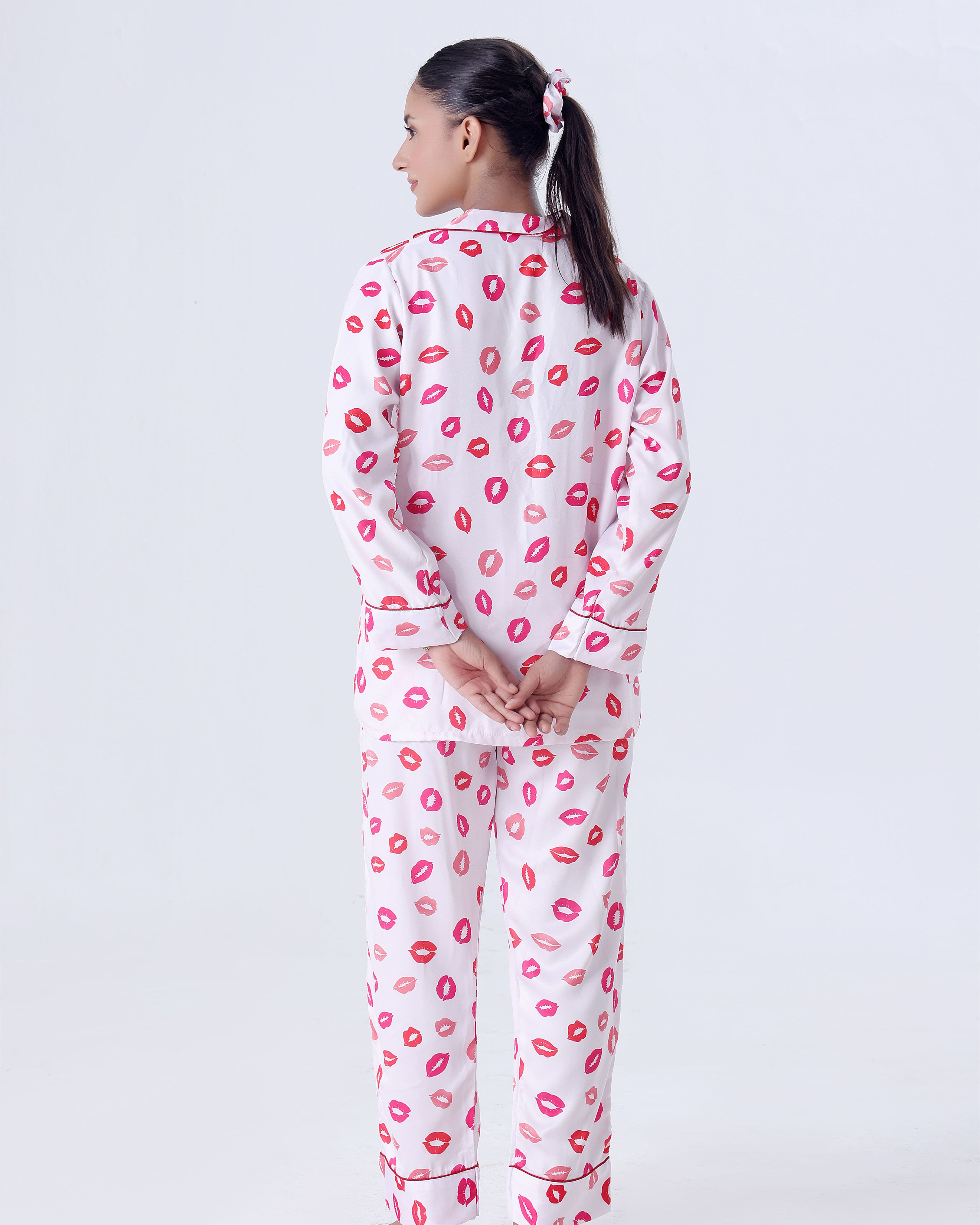Person wearing a white pajama set with pink lip prints on a white background