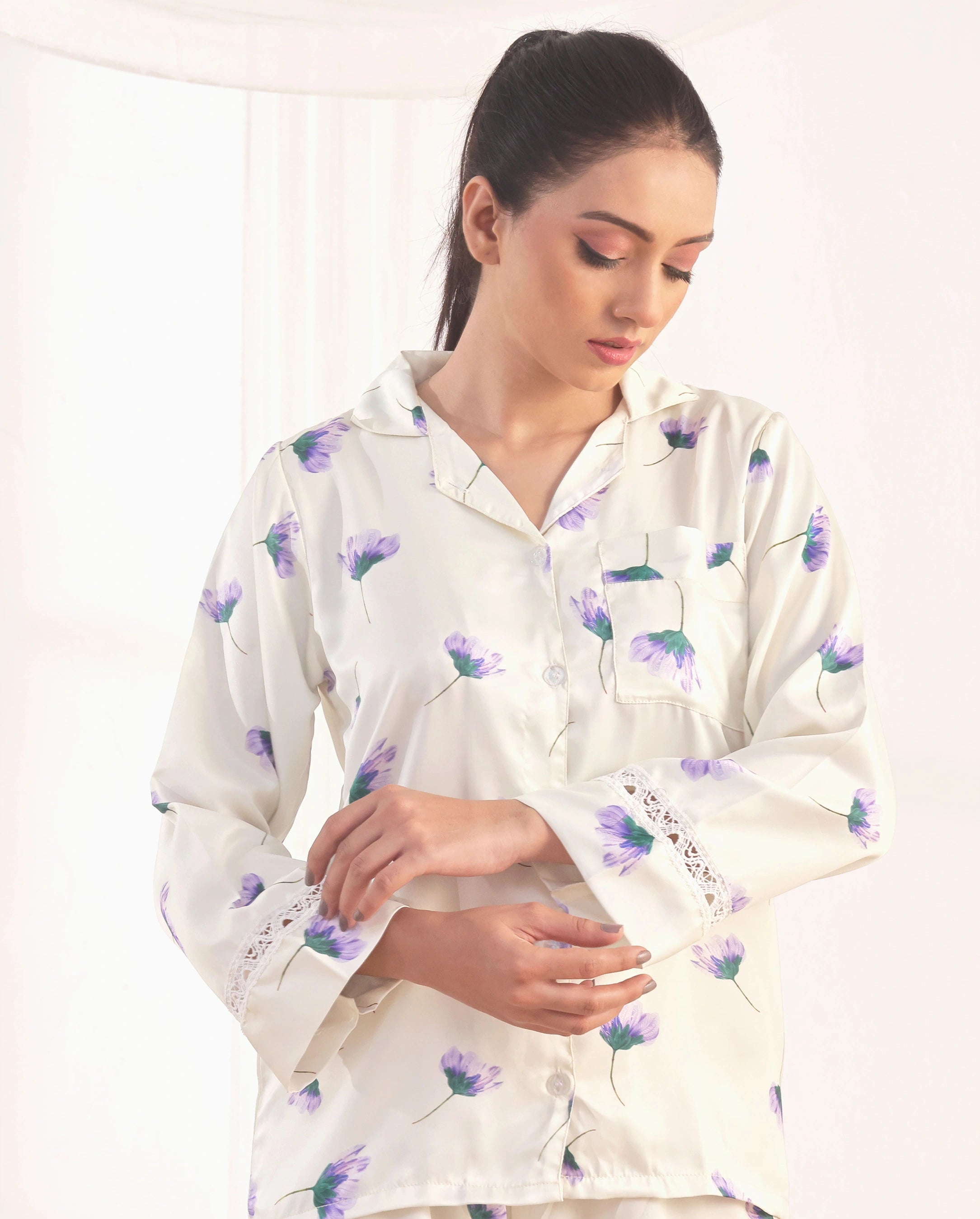 Woman wearing a white floral pajama set against a plain background